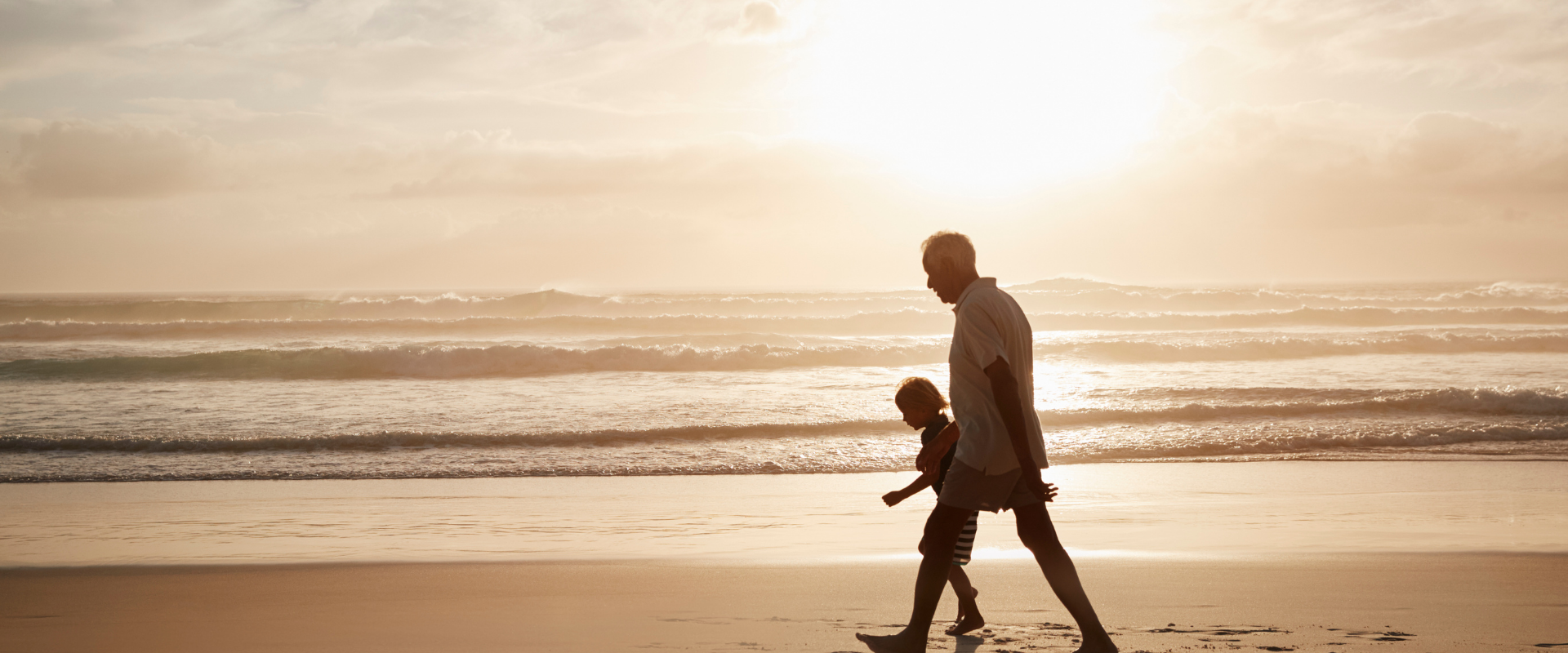 Elderly man walking with child on beach