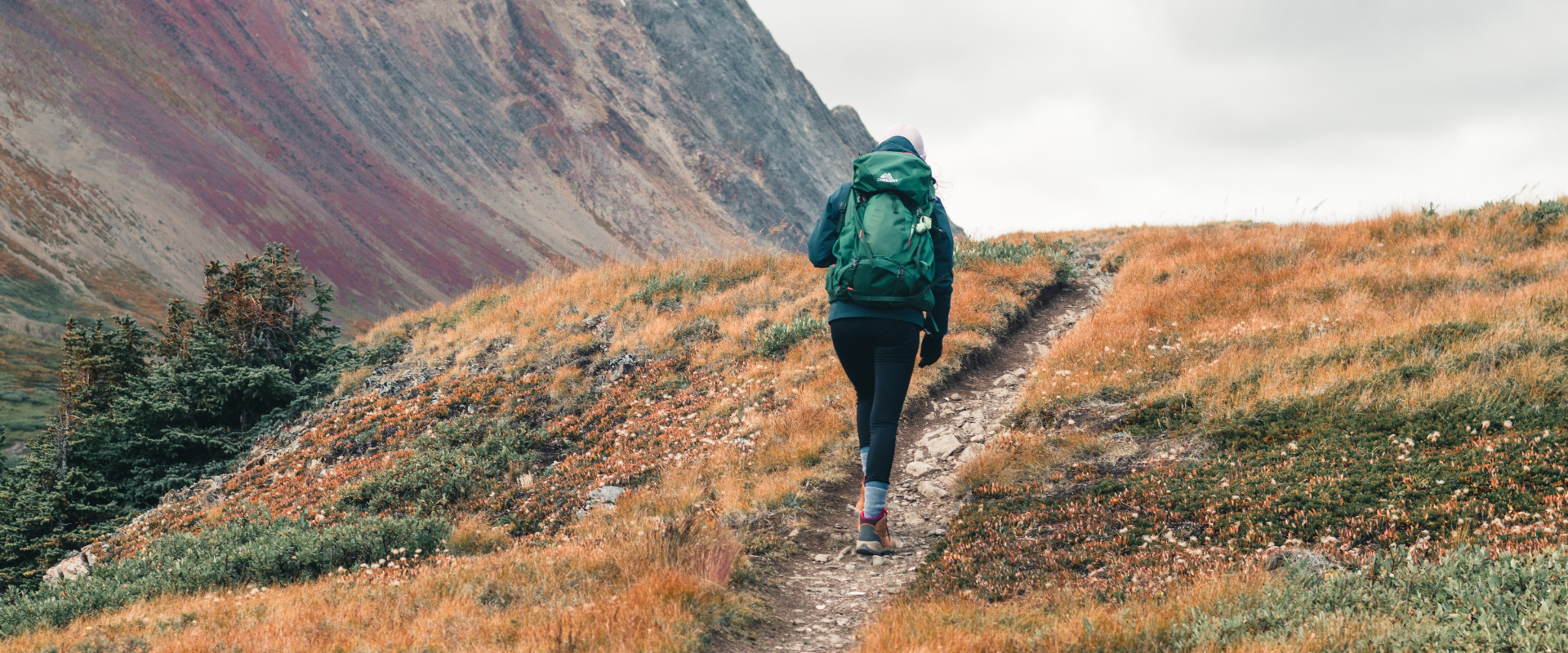 Person hiking on a mountain trail in autumn.