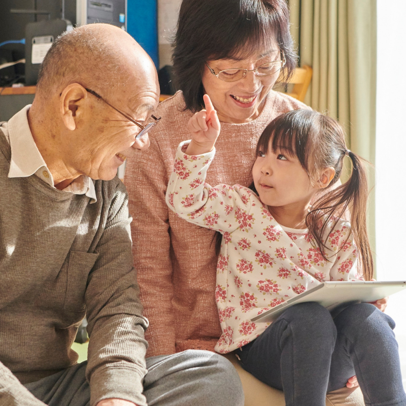 Grandparents spending time with granddaughter using tablet