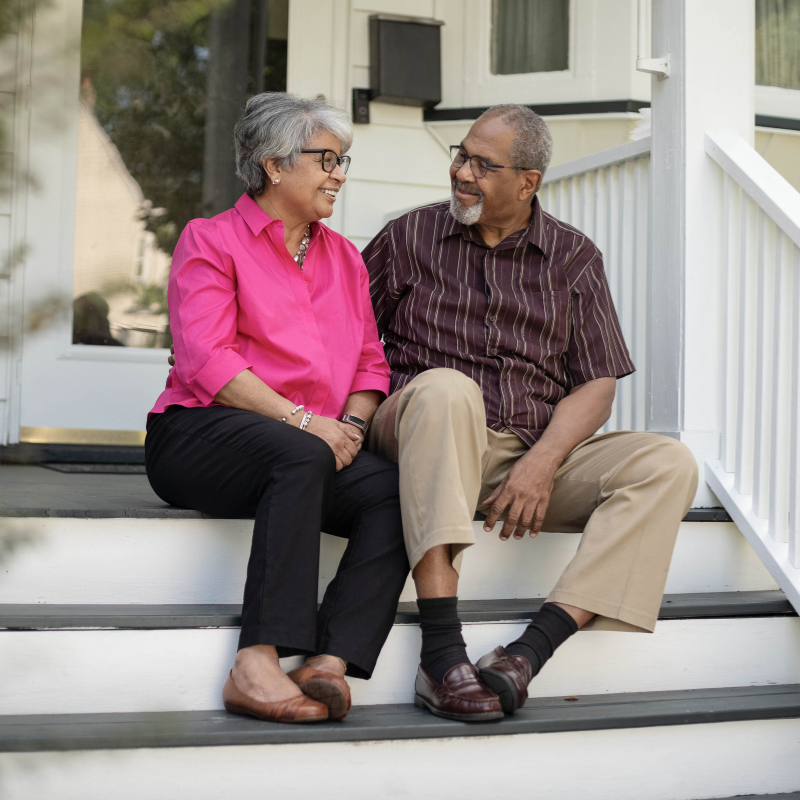 Smiling couple sitting together on front porch steps