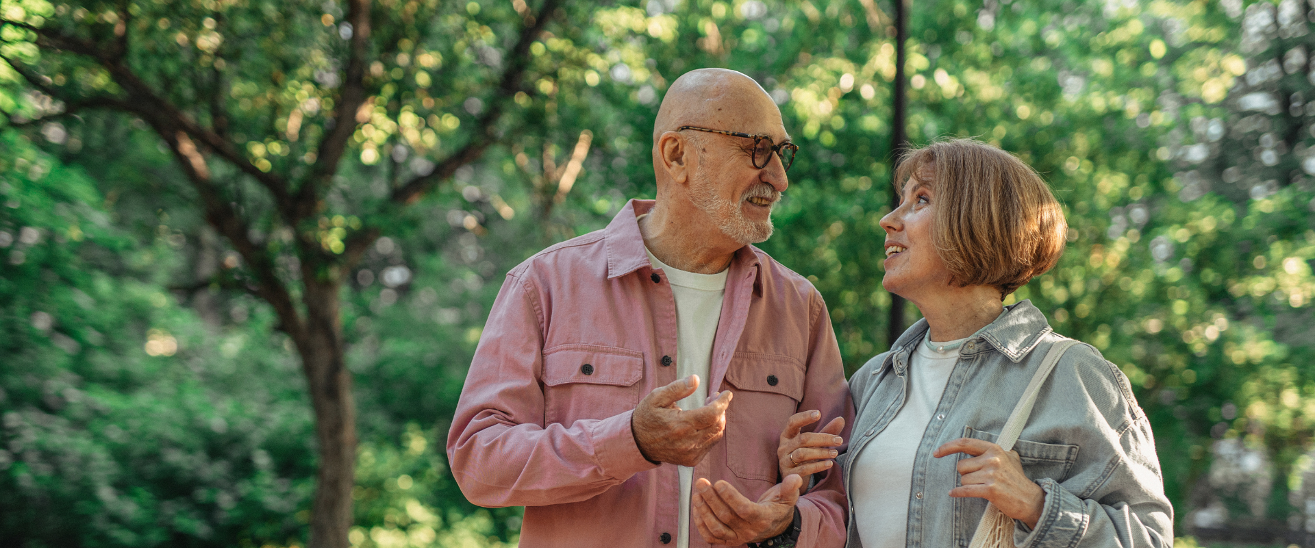 Older couple talking while walking in green park
