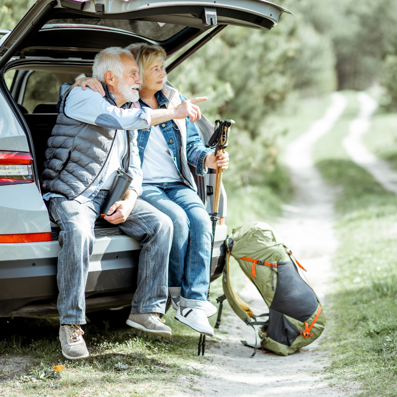 Senior couple resting by car during nature hike
