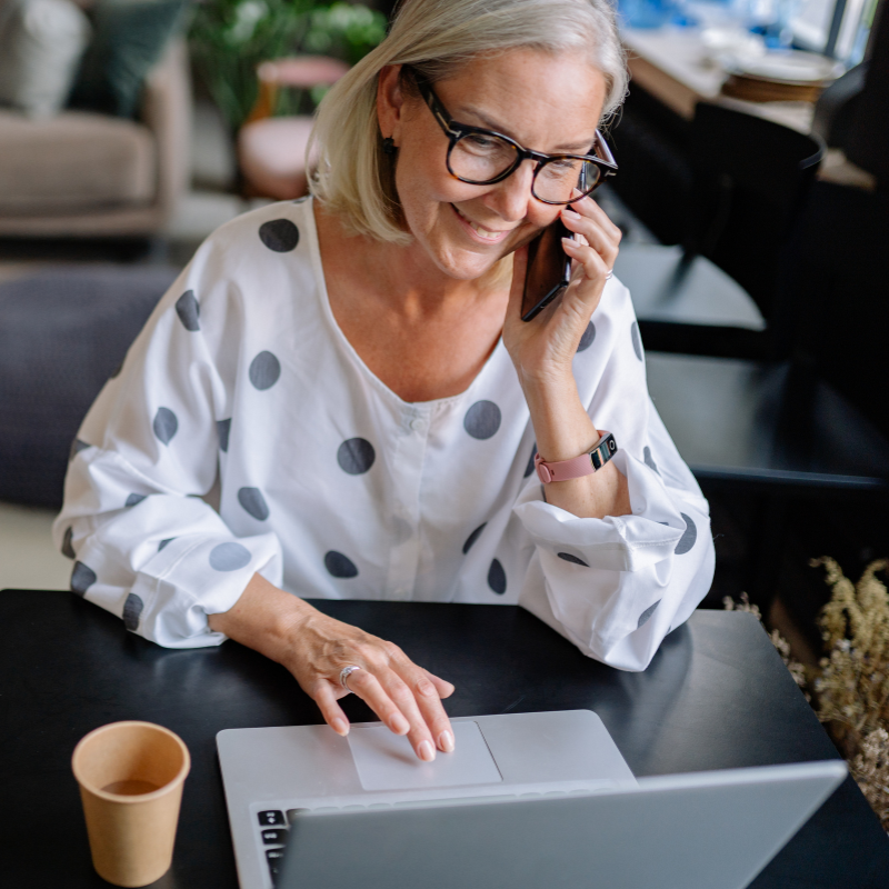 Woman smiling while talking on phone and using laptop