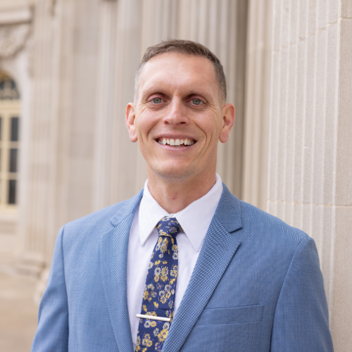 Smiling man in blue suit outside building