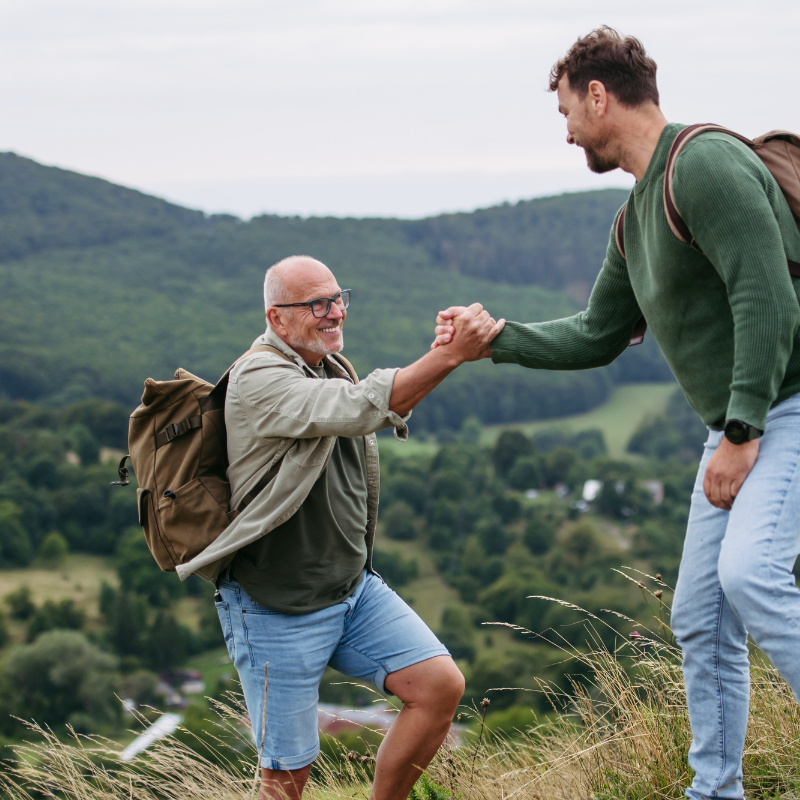 Two hikers helping each other on mountain trail